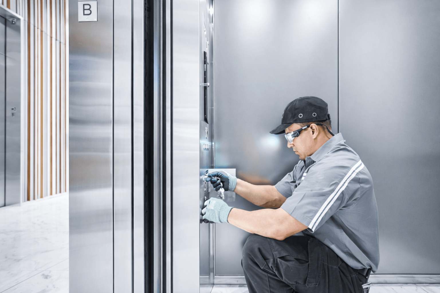 Elevator maintenance technician inspecting and repairing a modern elevator control panel.