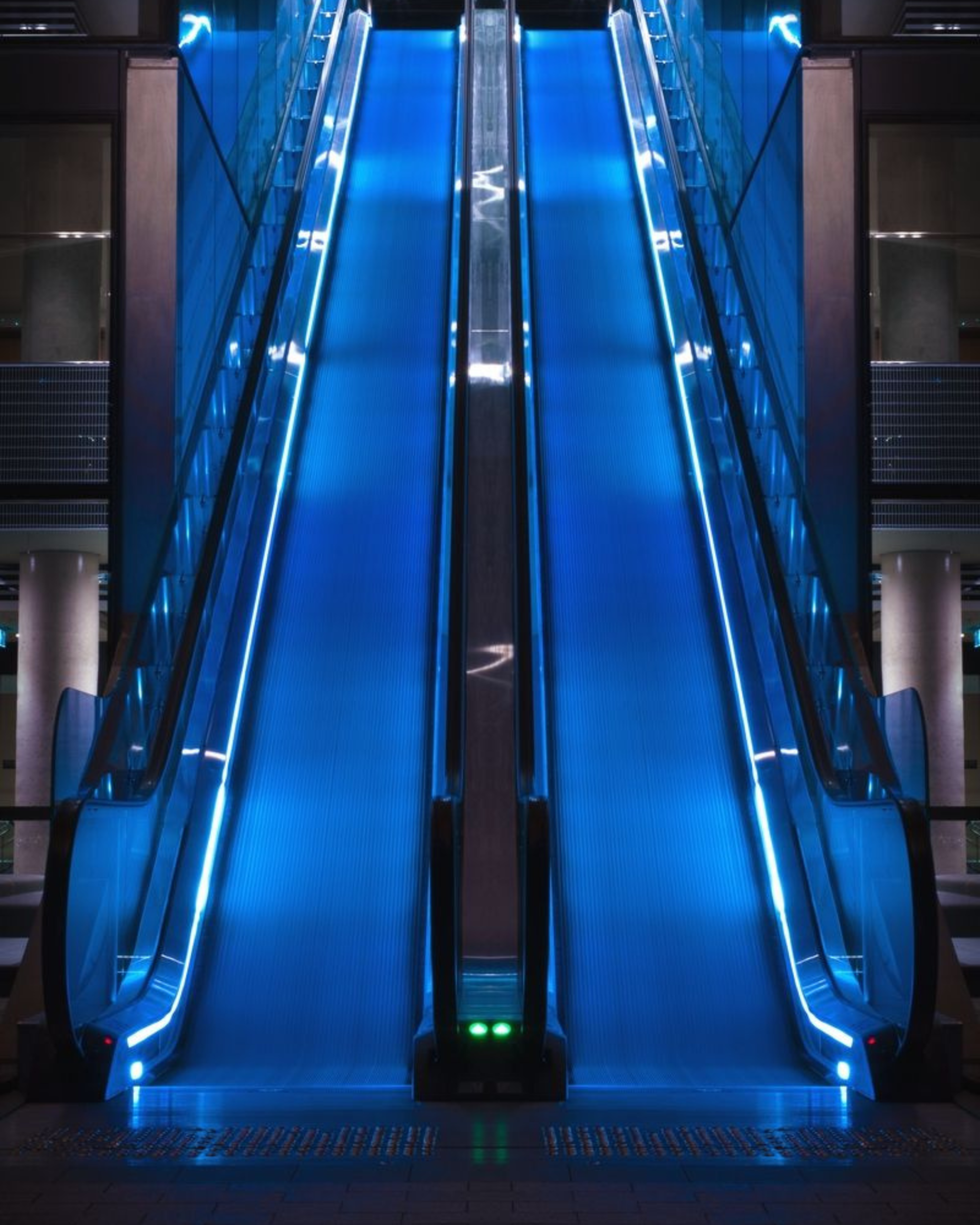 Modern blue-lit escalator inside a contemporary commercial building, designed for smooth and efficient vertical movement.